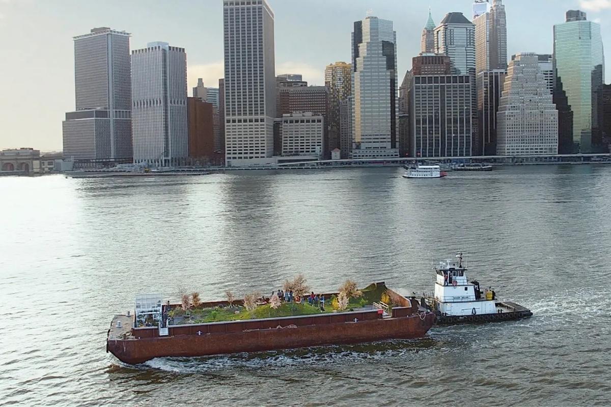 “Swale” (2017), by Mary Mattingly, a floating garden on a barge, with Lower Manhattan in the background. Photography courtesy of the artist and Cloudfactory.