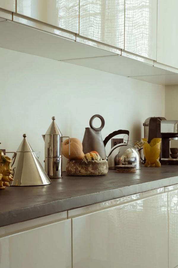 On the polished concrete benchtop in the kitchen, the couple’s collection of 1980s silver Alessi appliances and ceramics of Dries’s design. Photography by Matthew Avignone.