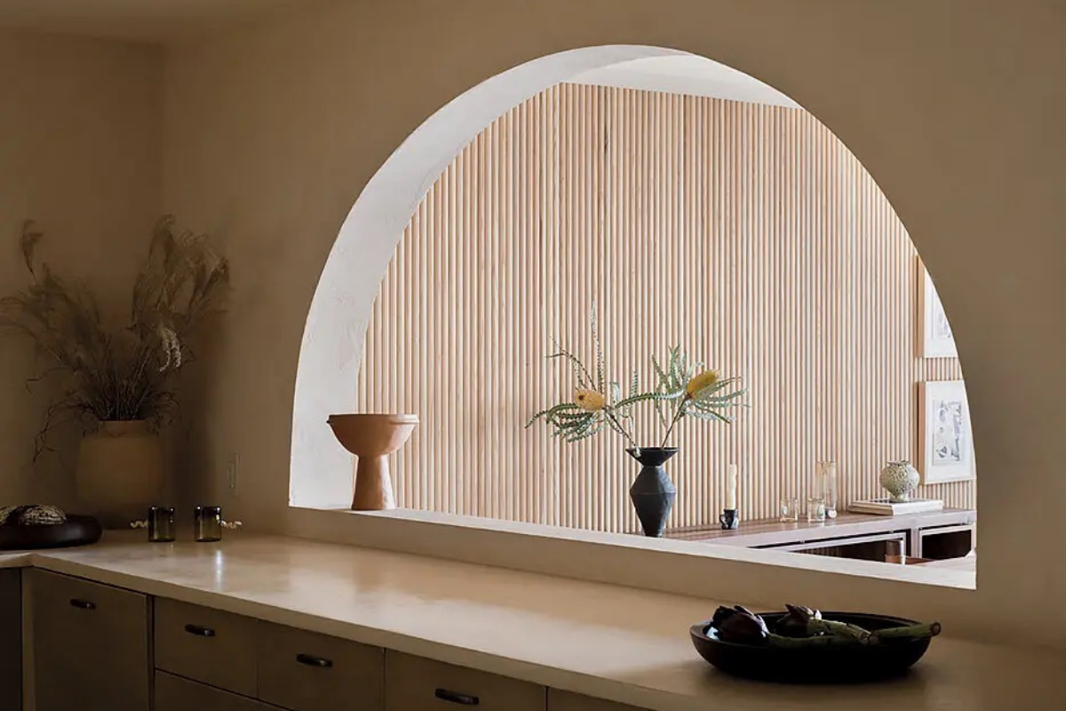 The pair cut an arched opening to connect the dining room to the kitchen. On the counter, a terracotta fruit bowl and a vessel by Marta Bonilla. Photography by Nicholas Calcott.