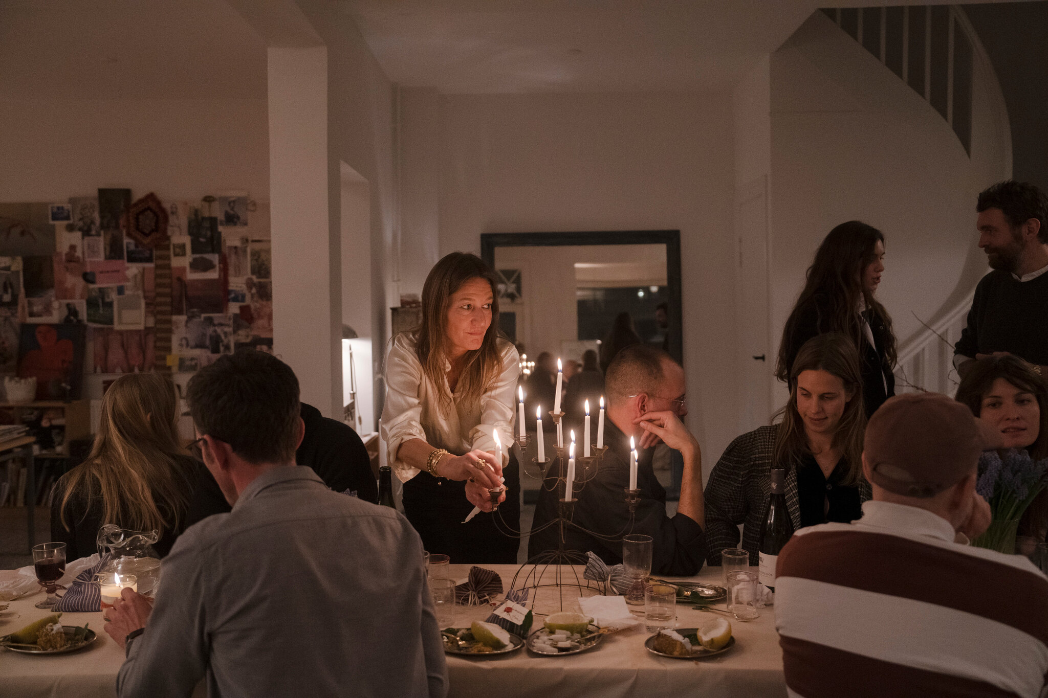 Dark room. Table lit by candles alone.