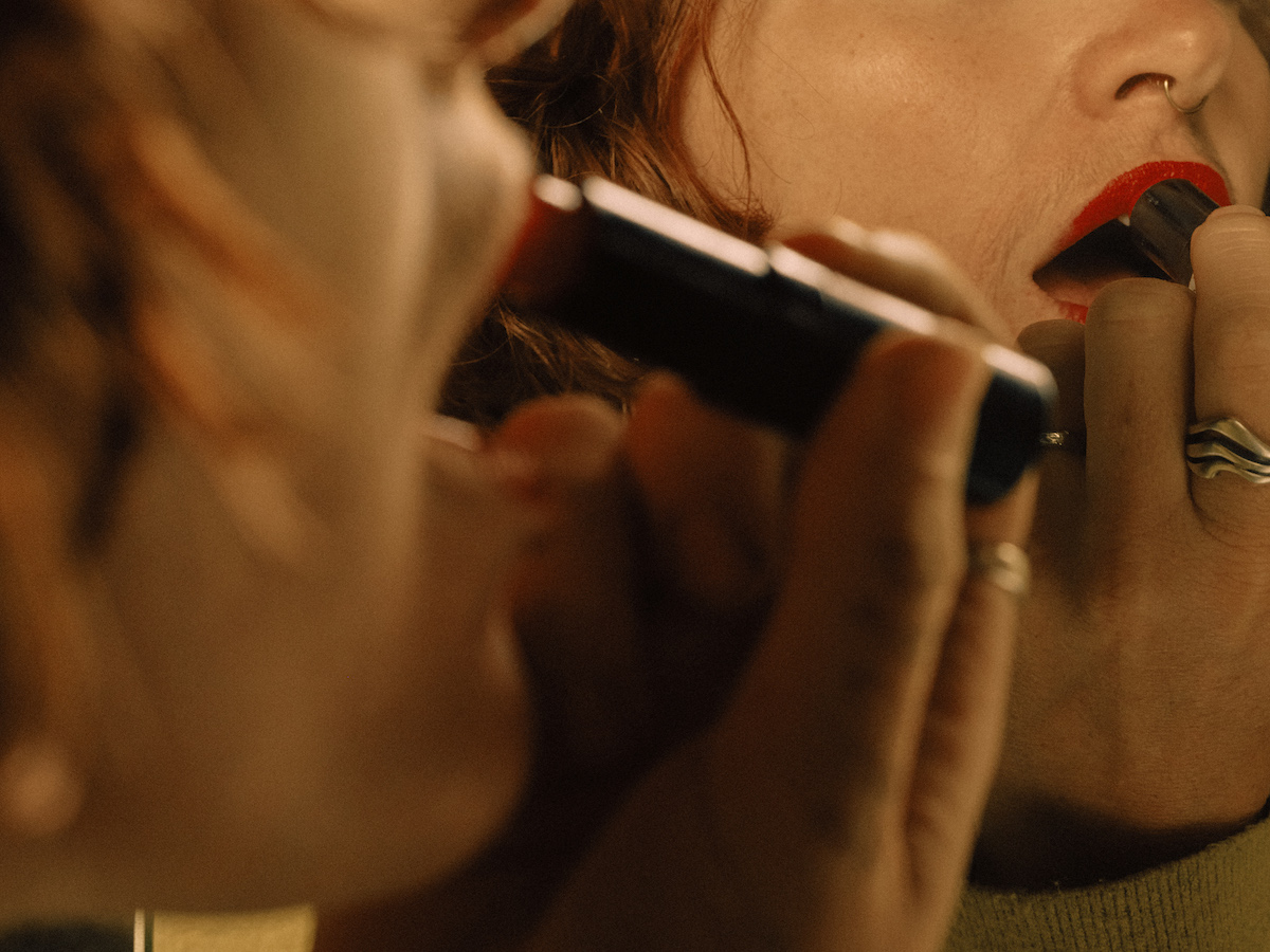 A person with facial hair applies lipstick in Italy in November 2024. (Lisa Sorgini/The New York Times)